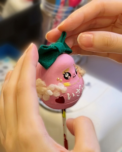 はっぴーだるまの製作風景です。頭にリボンをつけてあげています。